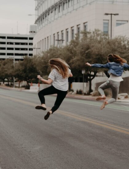 Photo by Kenny Eliason two woman jumping on the street during daytime